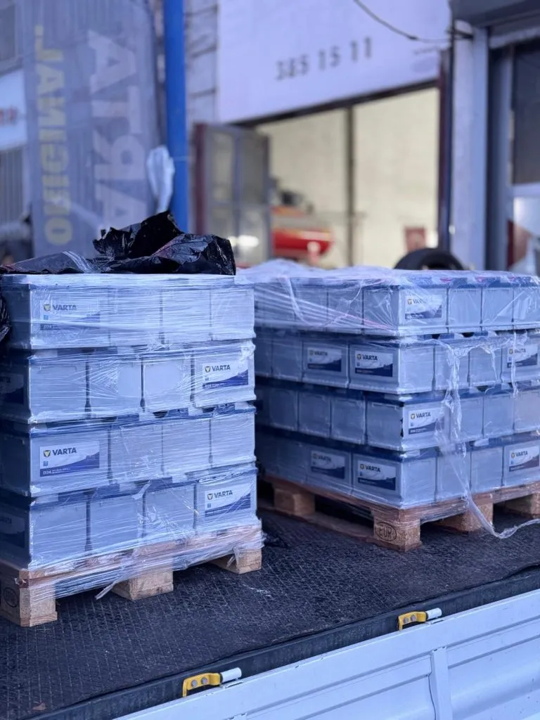 Kamyon kasasında akü paletleri, mağaza önünde